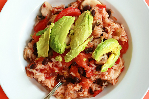 A big bowl of beans and rice topped with avocado is a cheap, tasty vegan meal.